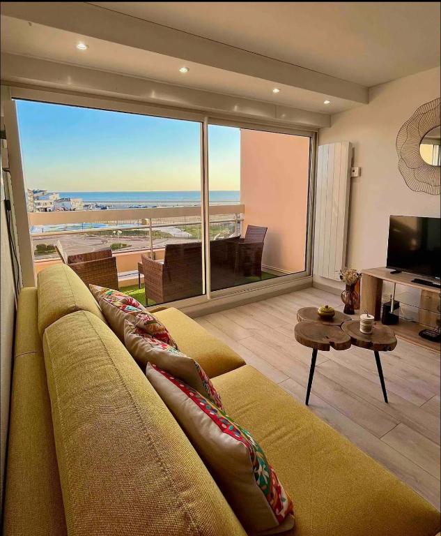 un salon avec un canapé et une vue sur l'océan dans l'établissement Le rêve bleu de Jeanne et Marie-vue mer, à Cucq