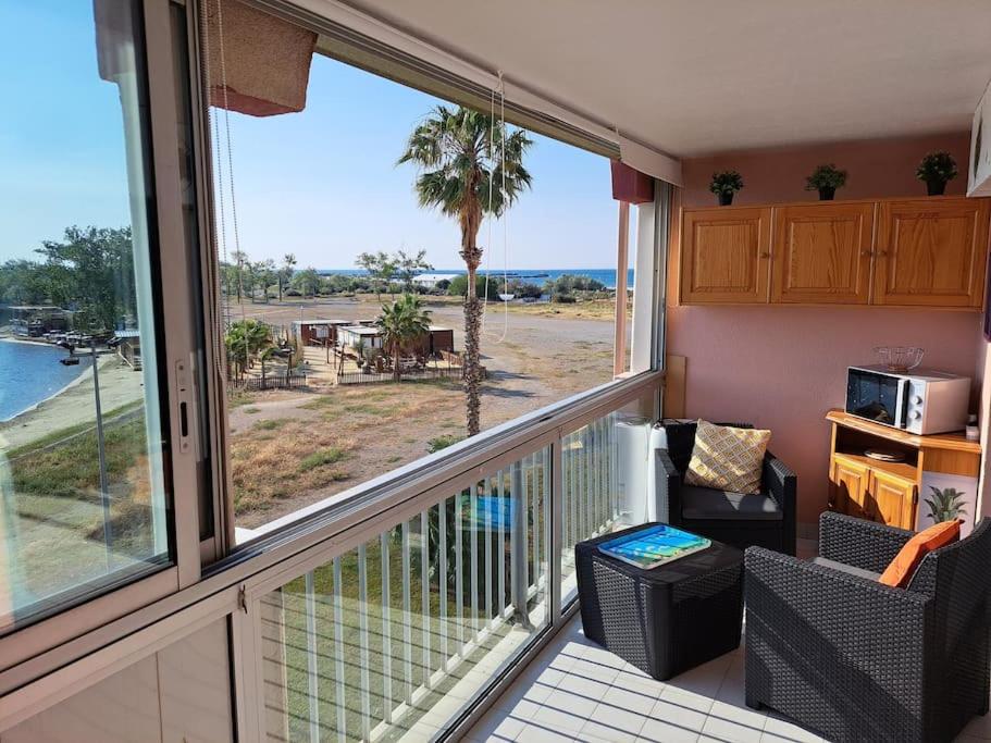 d'un balcon avec vue sur l'océan et un palmier. dans l'établissement Amoureva B35, T2 vue mer, parking, piscine, clim, au Cap d'Agde