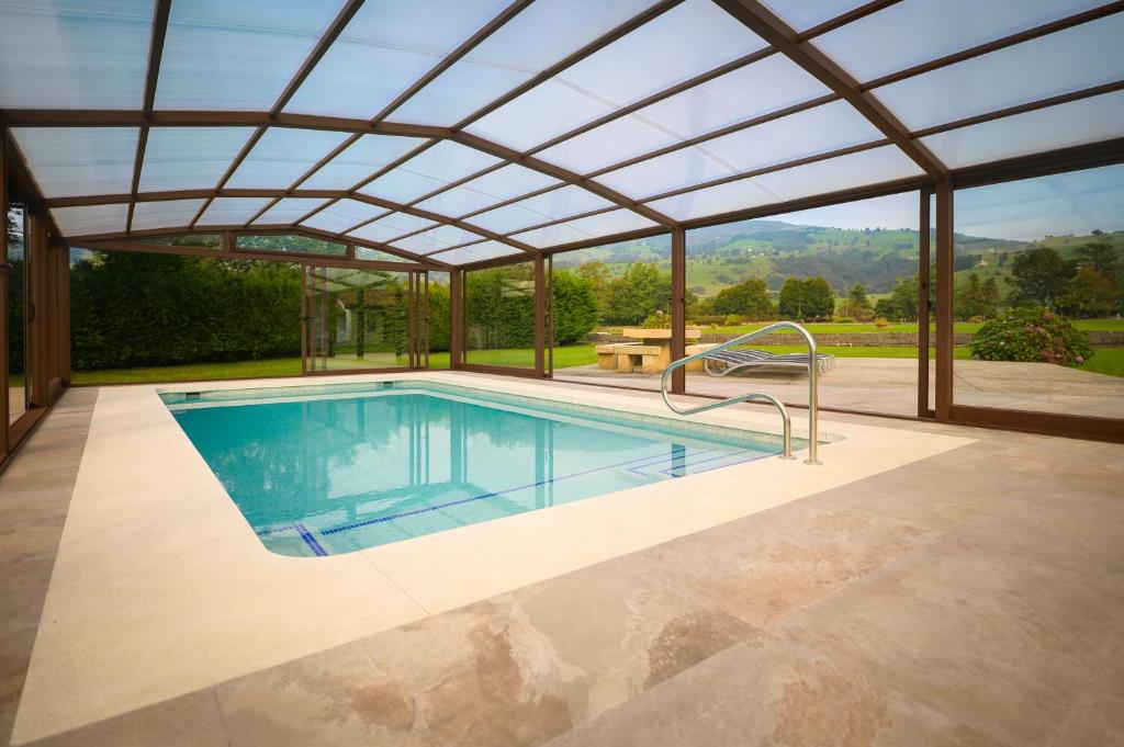 an outdoor pool with a pergola and a swimming poolvisor at Piscina climatizada y cubierta 365 dias en Casa Rural con Encanto El Puentuco una de las casas mas valoradas de Cantabria in Villacarriedo