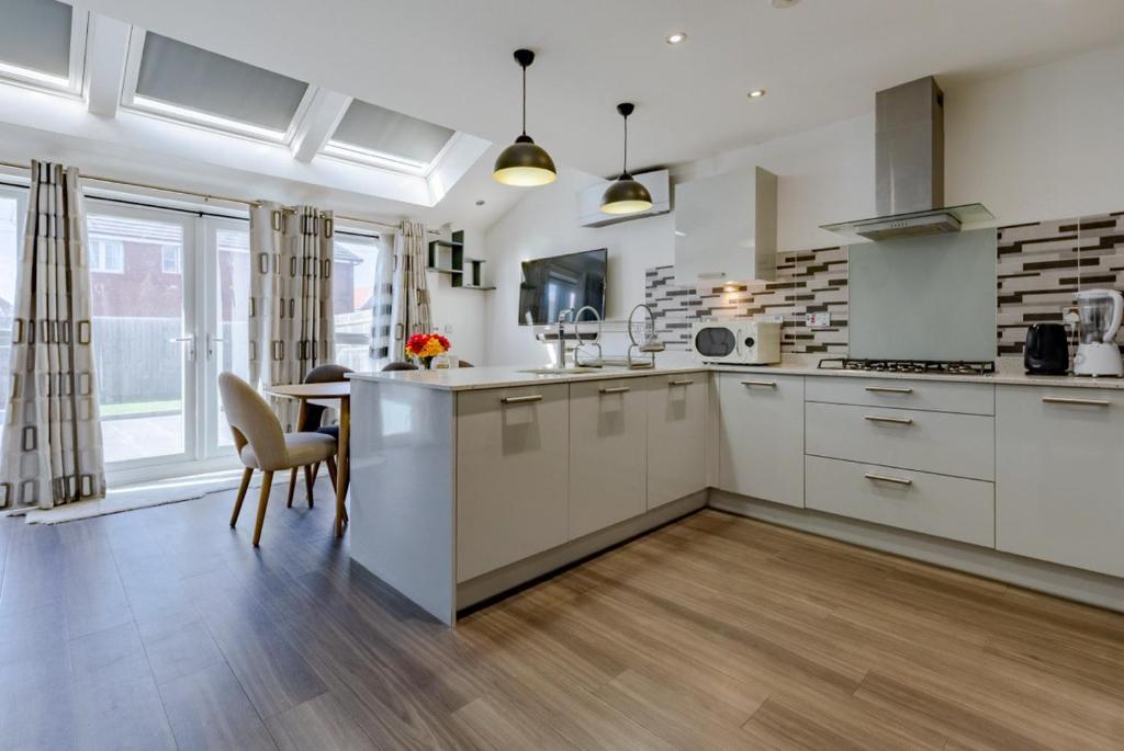 a kitchen with white cabinets and a table and chairs at Luxurious 2 Bed House near Birmingham in Bilston