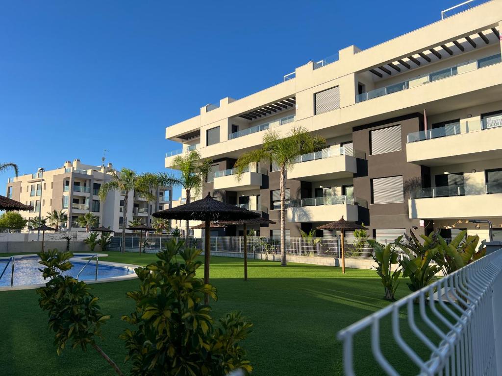 an apartment building with an umbrella in front of a yard at Poolside 2BR apartment Villamartin in Alicante