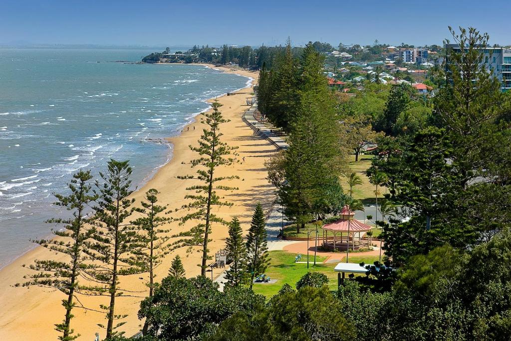 a view of a beach with trees and the ocean at Suttons Beach Apartments in Redcliffe