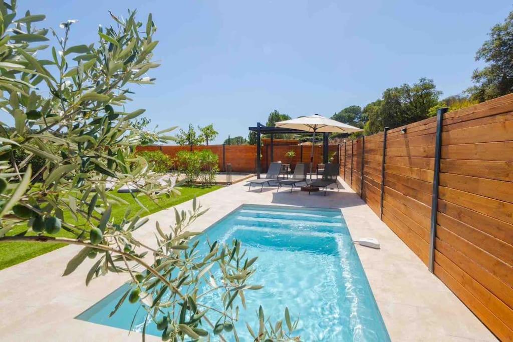 - une piscine dans un jardin avec une clôture en bois dans l'établissement Villa Maudroume, à Bormes-les-Mimosas