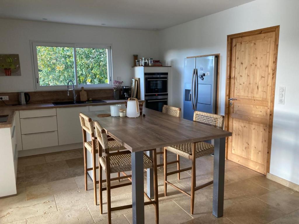 une cuisine avec une table en bois avec des chaises et un réfrigérateur dans l'établissement Agréable et confortable maison Le Vigan en Quercy, au Vigan