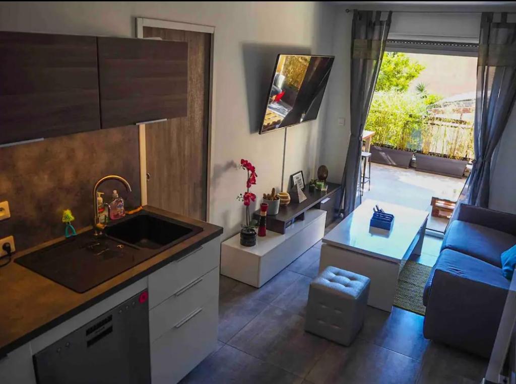 une cuisine avec un évier, un canapé et une fenêtre dans l'établissement Appartement au cœur du lavandou - plage à 200m, au Lavandou