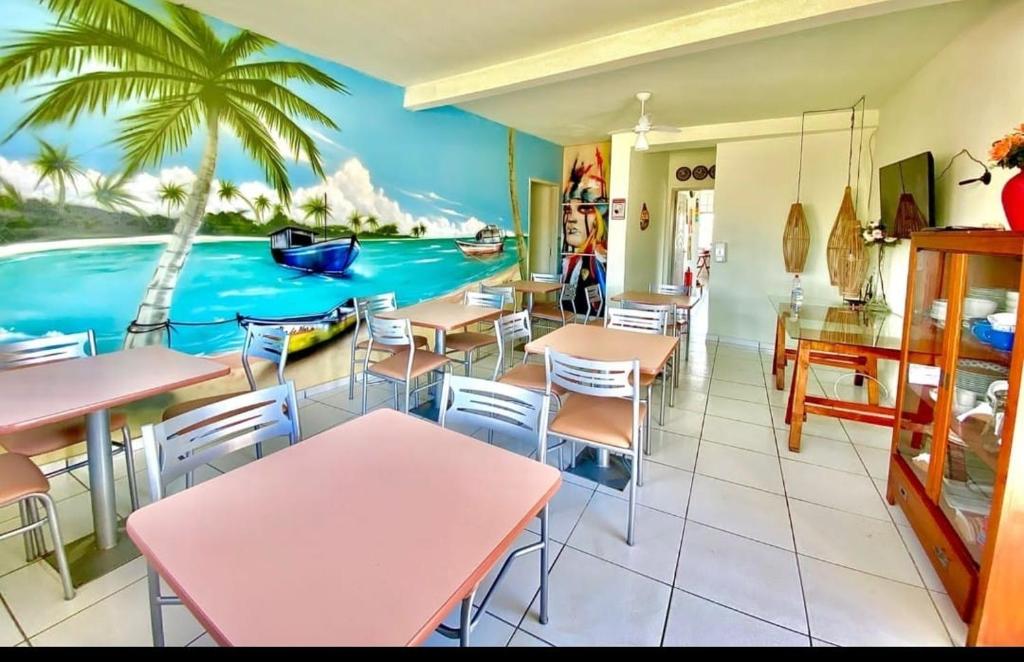 un restaurant avec des tables et des chaises et une fresque d'une plage dans l'établissement Pousada Caminho do Mar, à Santa Cruz Cabrália