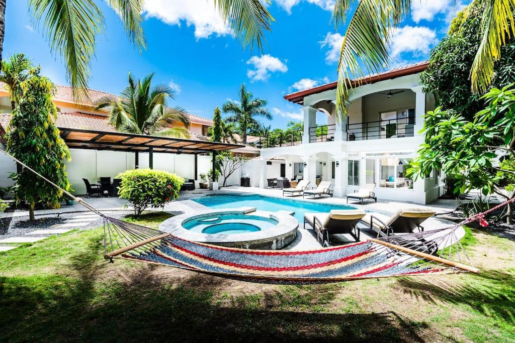 an image of a house with a hammock in the yard at Barefoot Beachfront, Pool, Surf & Private Casita in Playa Grande