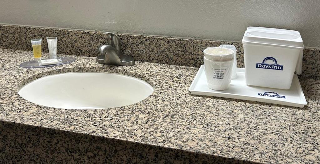 a bathroom counter with a sink and a cup of coffee at Days Inn by Wyndham Clayton in Clayton