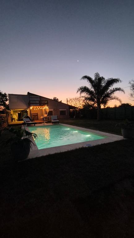 a swimming pool in front of a house with a palm tree at Campomar in Balneario Buenos Aires