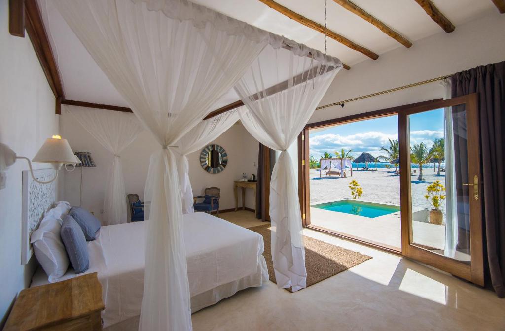 1 dormitorio con cama y vistas a la piscina en Konokono Beach Resort and Isaraya Luxury Overwater Villas, en Michamvi