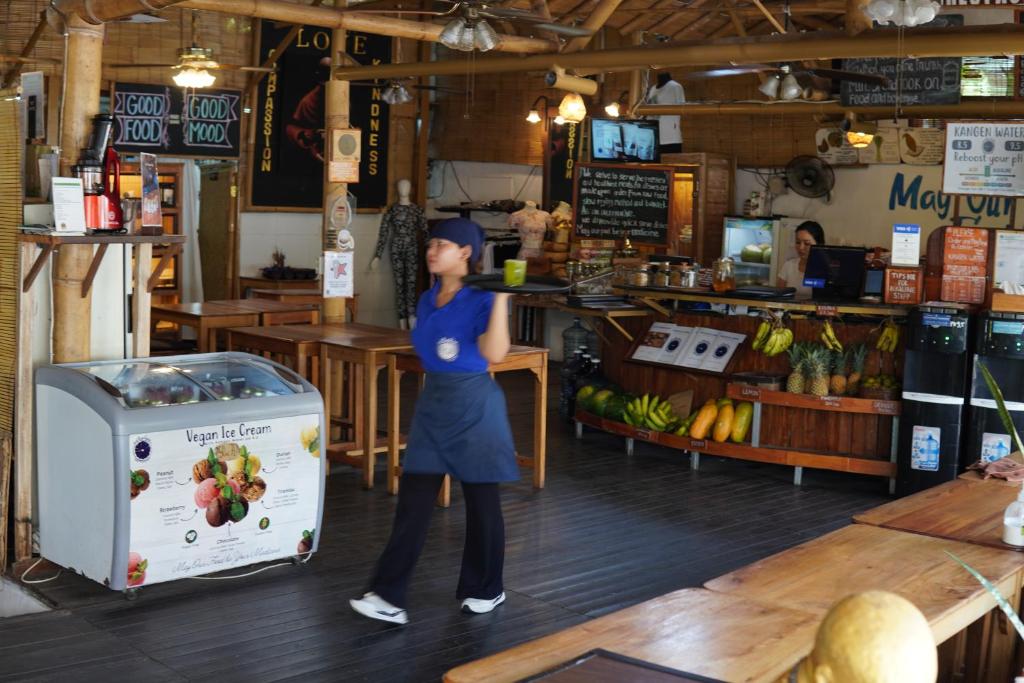 une femme debout à côté d'un comptoir dans un magasin dans l'établissement Serenity Eco Guesthouse - CHSE certified, à Canggu