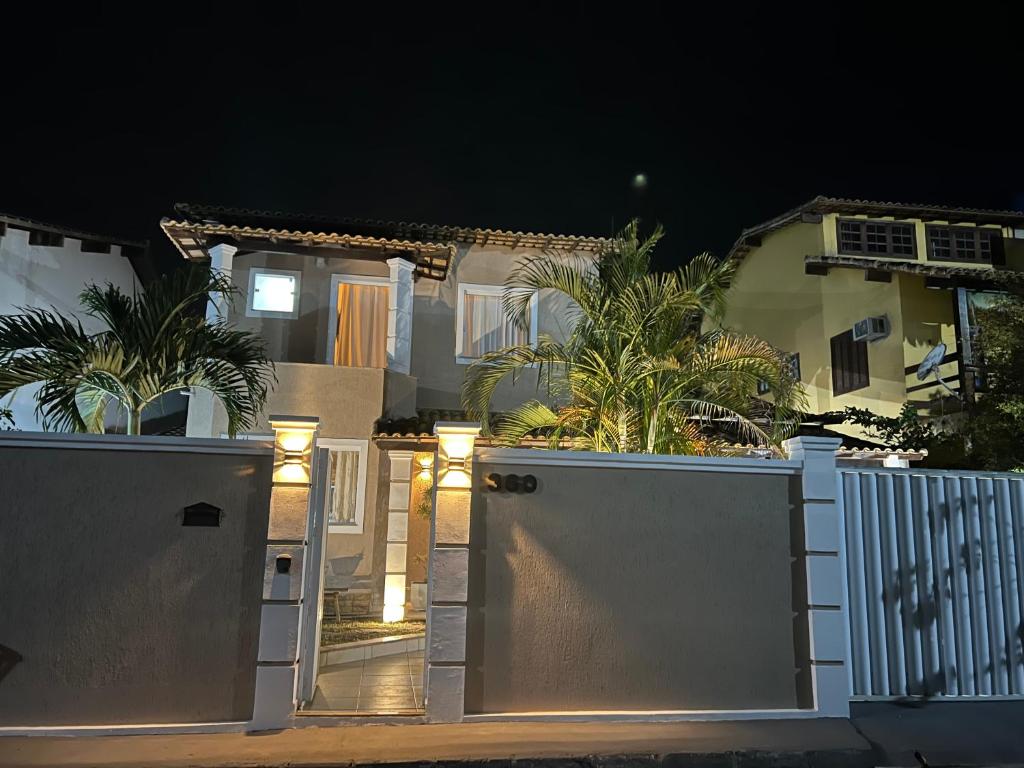 a white gate in front of a house at night at Casa com piscina, churrasqueira e ar condicionado em condomínio in Cabo Frio