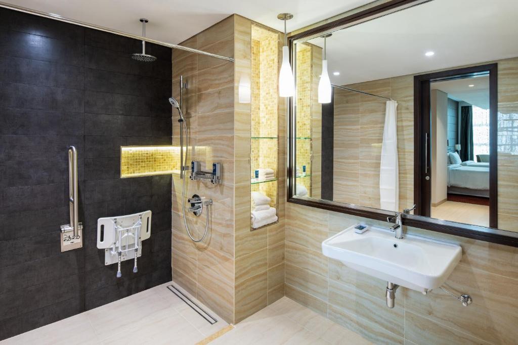 ein Bad mit einem Waschbecken und einer Dusche mit einem Spiegel in der Unterkunft Four Points by Sheraton Sharjah in Schardscha