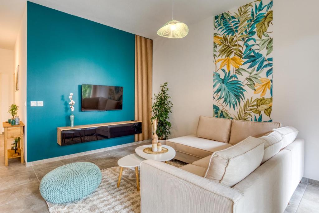 un salon avec un canapé et un mur bleu dans l'établissement Chic Marianne - Appt T2 Parking et Terrasse privés, à Montpellier