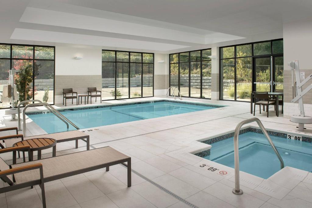 a large swimming pool with tables and chairs and windows at Courtyard Portland East in Portland