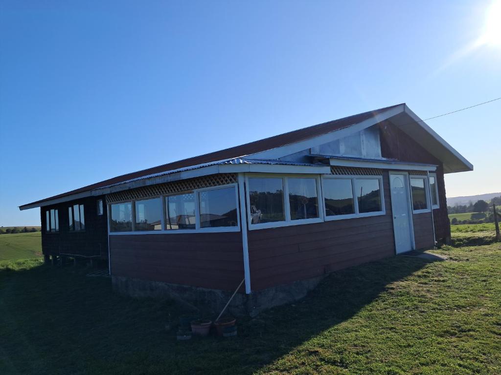 a small house with a large window on a field at Hermosa Casona en los Muermos in Los Muermos