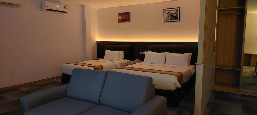 a hotel room with two beds and a couch at Al Afiah Hotel in Bandar Seri Begawan