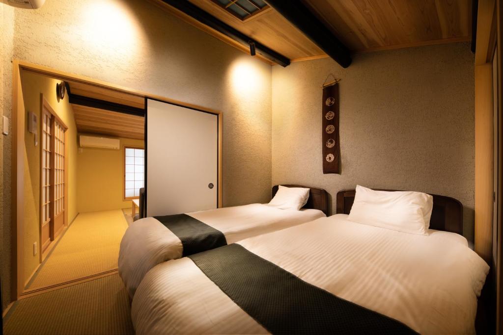 two beds in a small room with a door at Connect inn Kyoto-Gojo in Kyoto