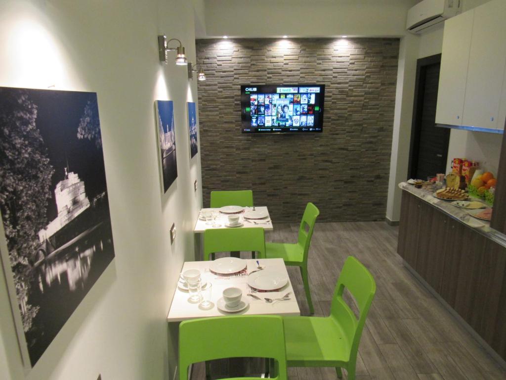 una sala da pranzo con tavoli e sedie verdi e una TV di Pianeta Roma a Roma