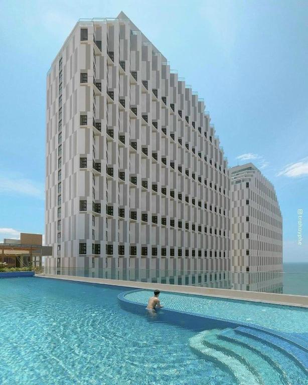 a man in a pool in front of a building at Apec Mandala Imperial Ocean Tower Mui Ne in Mui Ne