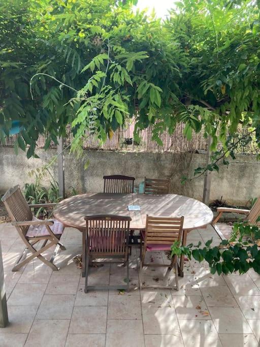 une table et des chaises en bois sous un arbre dans l'établissement Maison 3 chambres 1km de plage, à Six-Fours-les-Plages