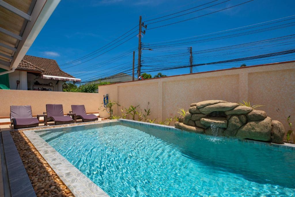 una piscina con 2 tumbonas junto a una casa en Coral Lagoon Pool Villa Rawai - Adult Only, en Rawai Beach