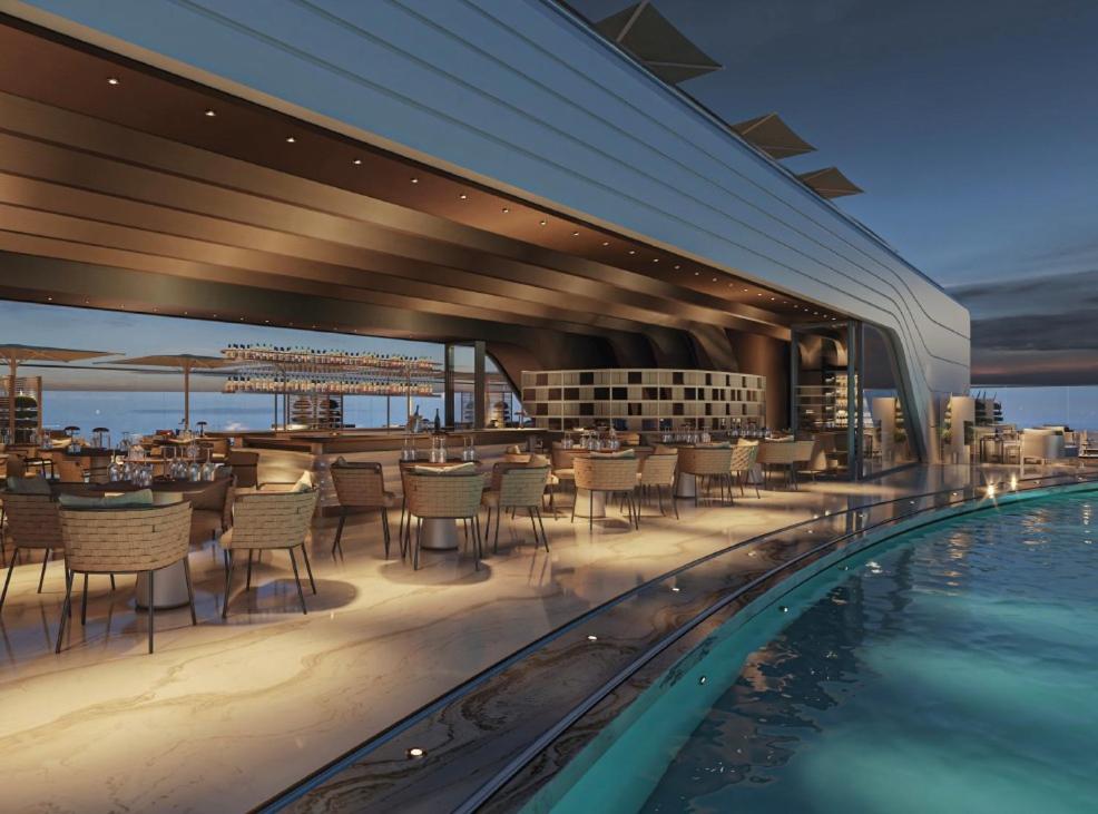 a restaurant with a pool and tables and chairs at The Signature Suite in Mercury Tower in St. Julianʼs