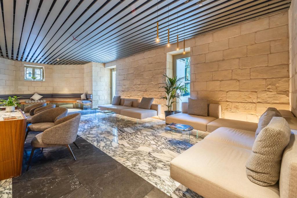 a lobby with couches and chairs and a stone wall at The Signature Suite in Mercury Tower in St. Julianʼs