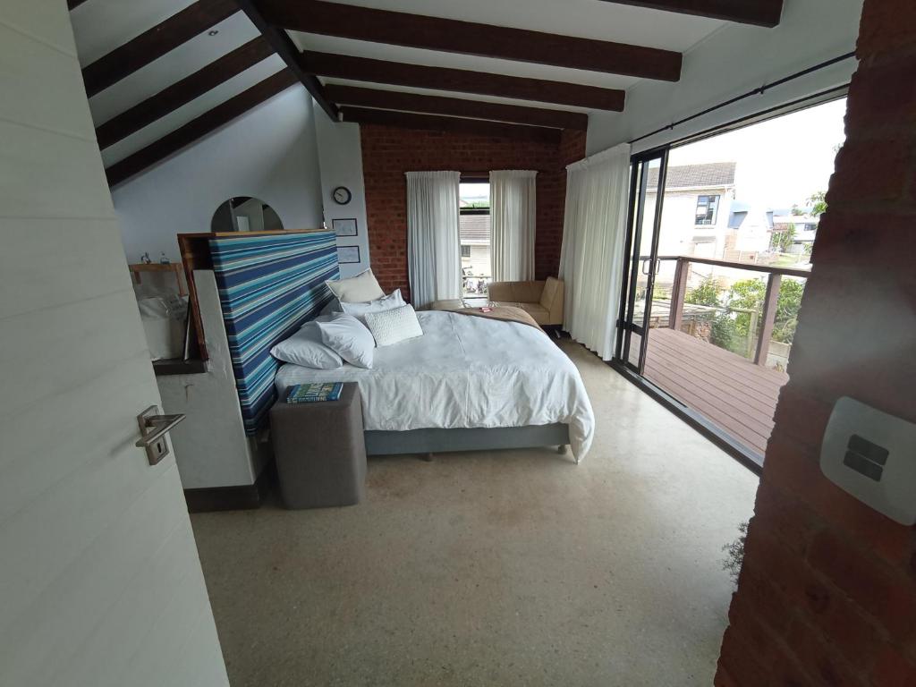 a bedroom with a bed and a balcony at Jbay Holiday Home in Jeffreys Bay