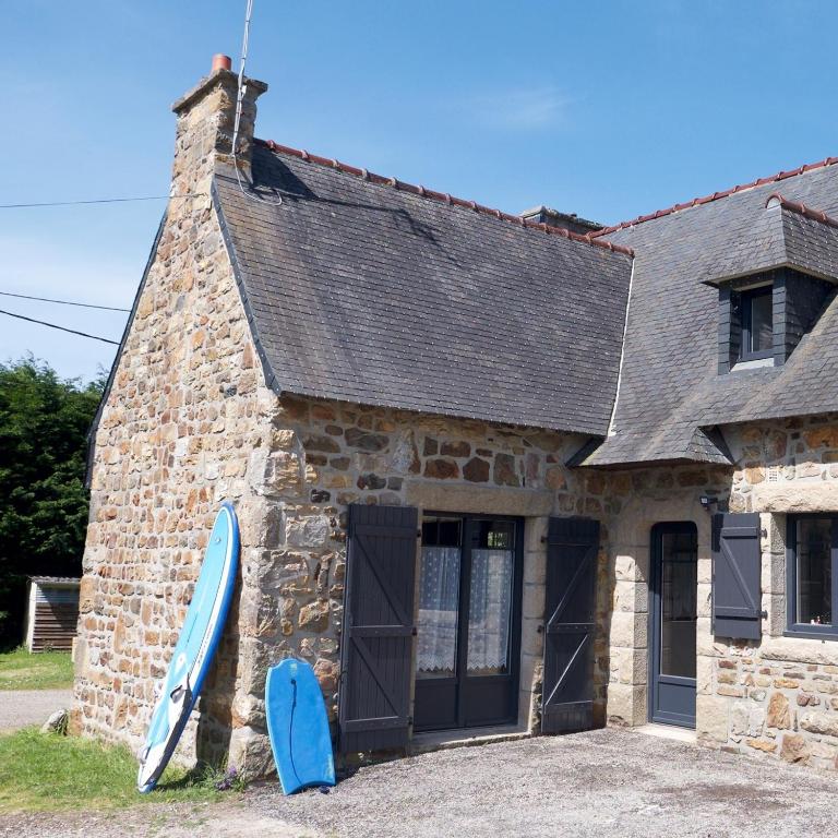 une maison avec deux planches de surf bleues assises à l'extérieur dans l'établissement Maison bretonne entre terre et mer, à Crozon