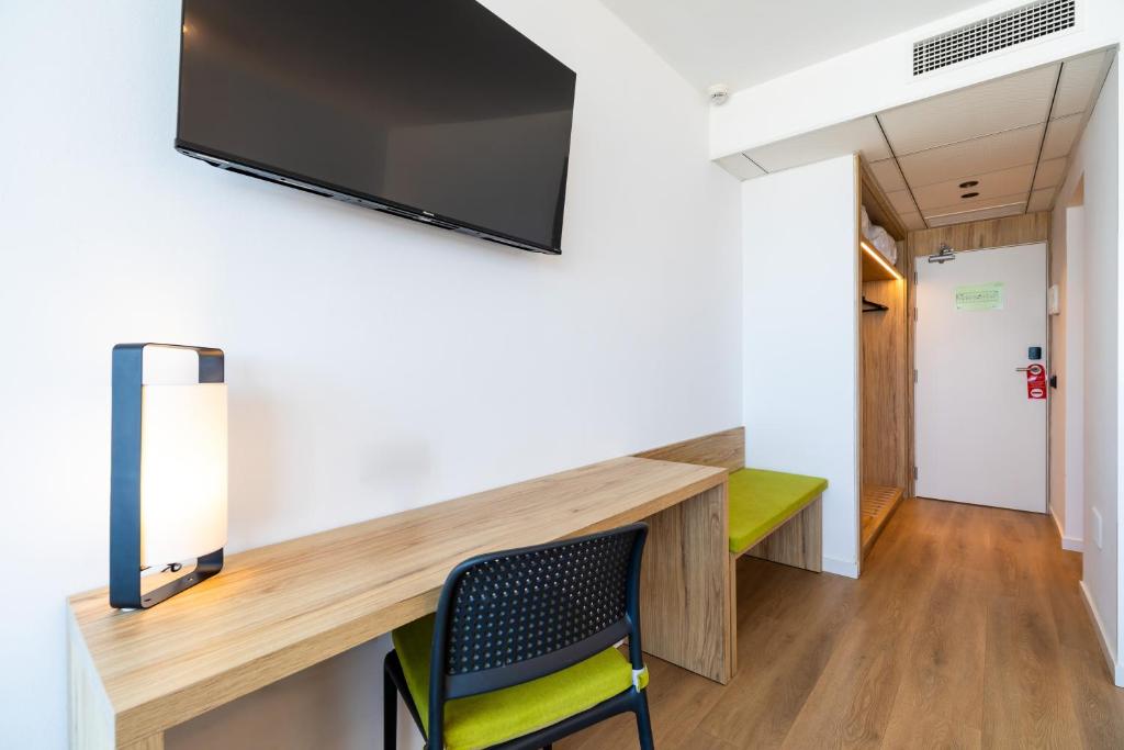 a room with a wall mounted tv and a chair at Ohtels Carabela in Matalascañas