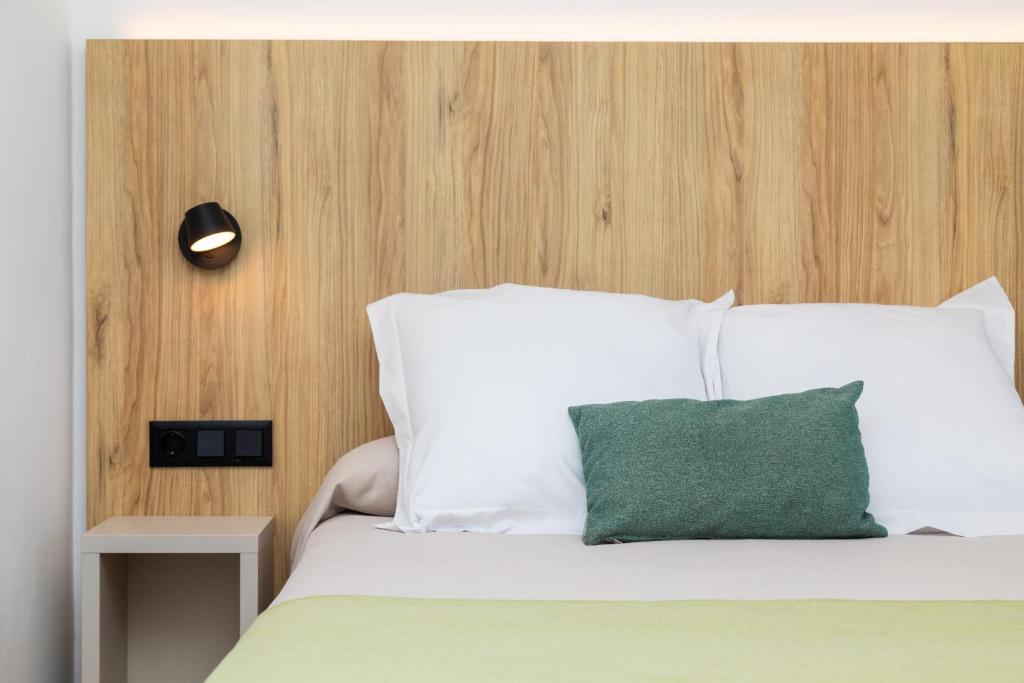 a bedroom with a white bed with a green pillow at Ohtels Carabela in Matalascañas