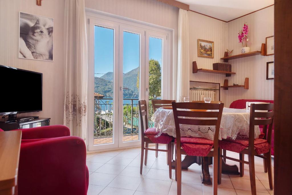 a dining room with a table and a large window at Casa Rosanna al lago in Maccagno Inferiore
