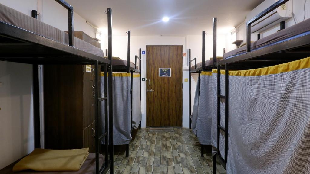 a room with two bunk beds and a door at BunkNBrew in Palolem
