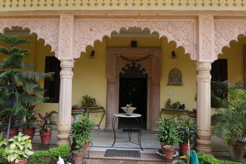 ein Eingang zu einem Haus mit einem Tisch und Topfpflanzen in der Unterkunft The Boho Heritage Haveli in Jaipur