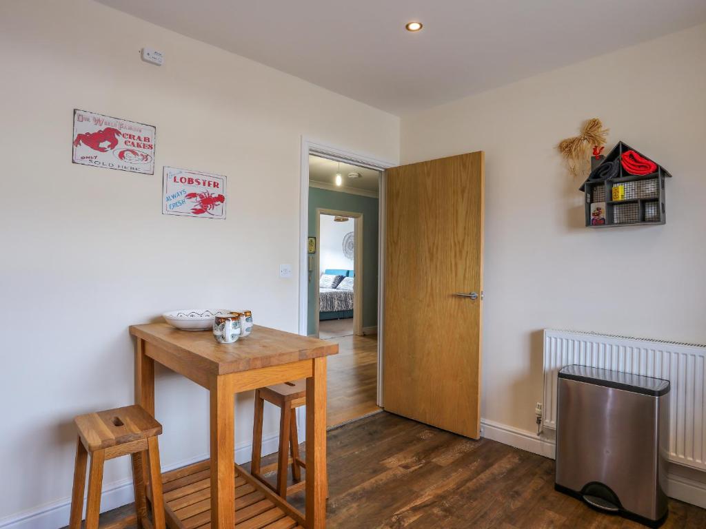 a room with a wooden table and a door and a table and stool at Tides Reach in Rhosneigr