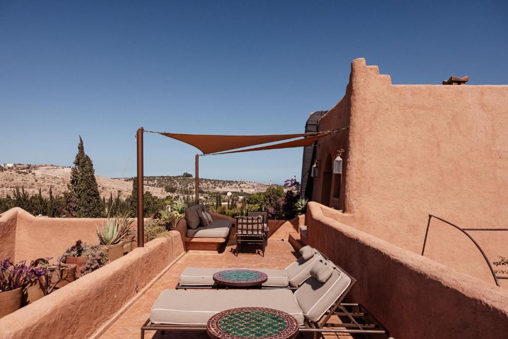 a patio with a couch and a table on a house at Le Jardin des Douars in Ghazoua