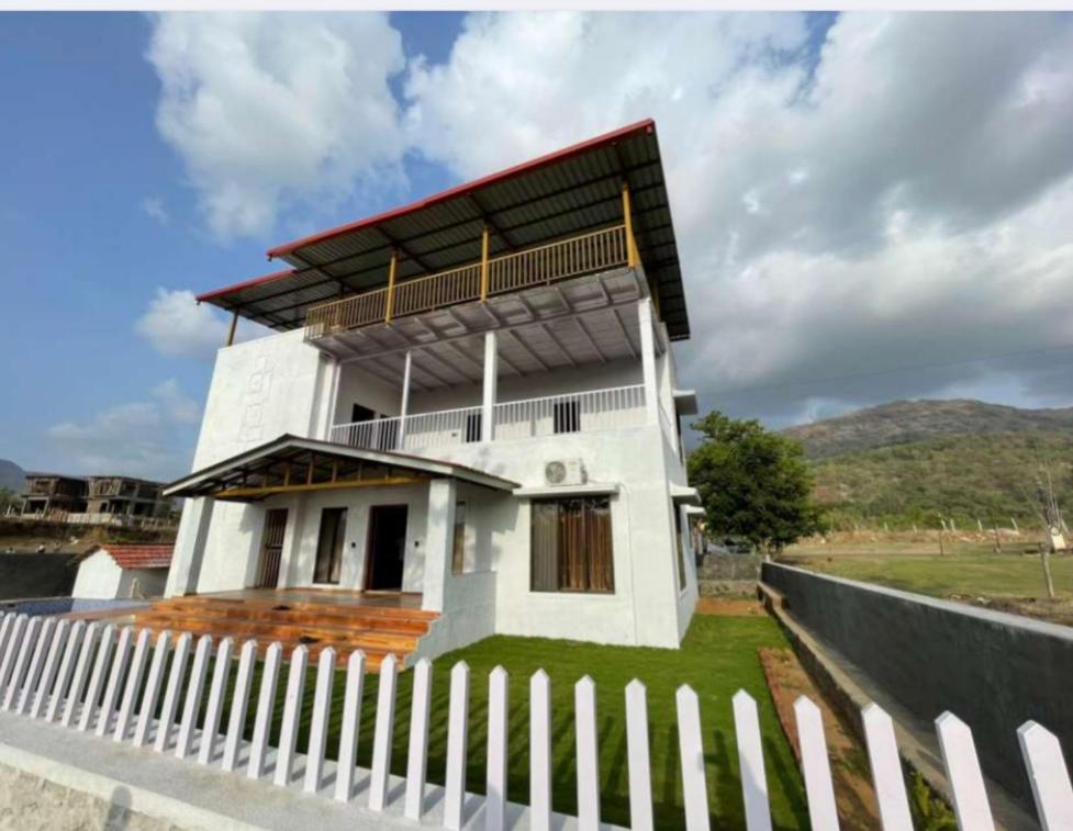 Biały dom z płotem przed nim w obiekcie Villa Montagna By Nutan Holidays w mieście Karjat