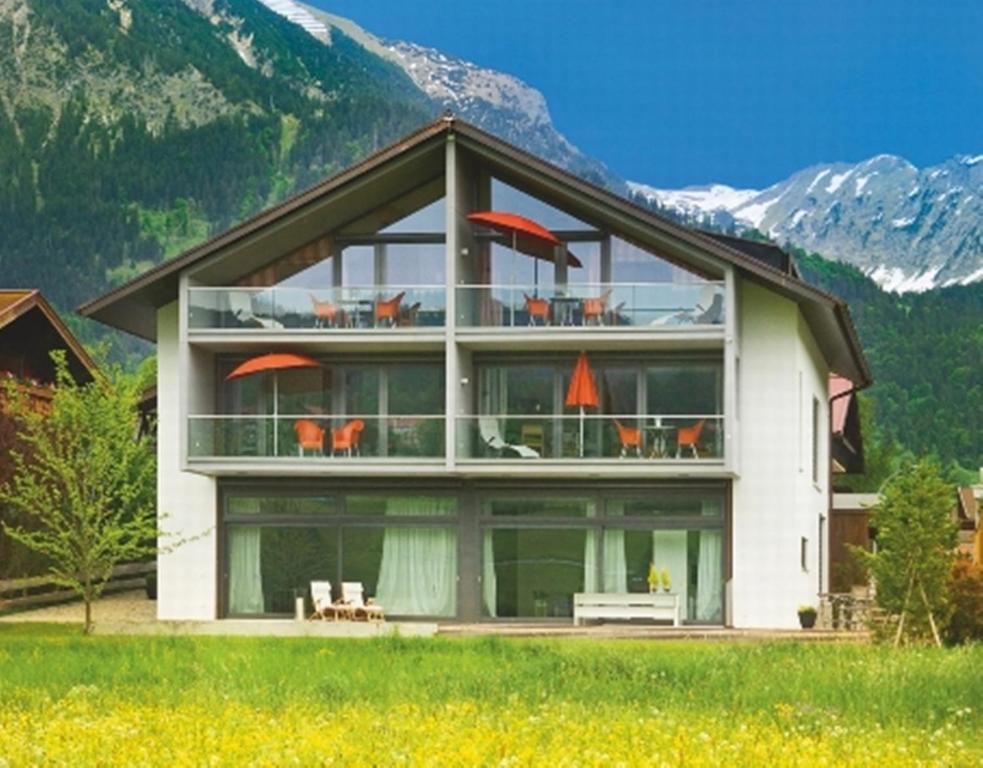 ein großes weißes Haus mit Bergen im Hintergrund in der Unterkunft Bergzeit Ferienwohnungen in Oberstdorf