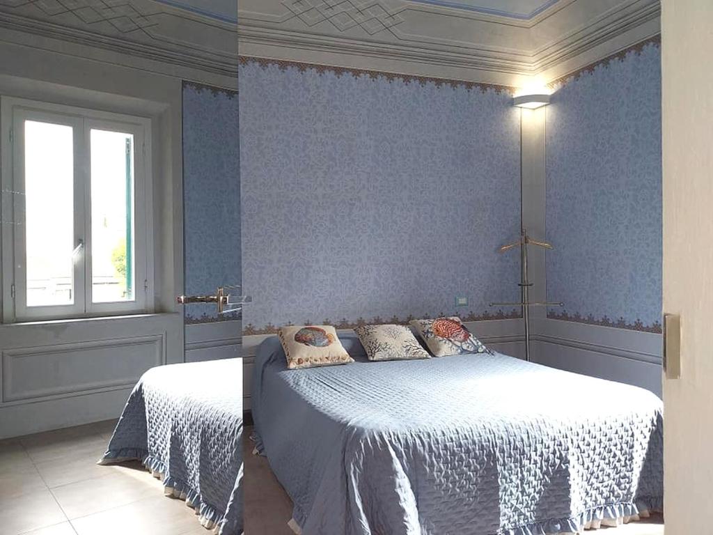 a blue bedroom with a bed and a window at Ampio appartamento di Charme con 2 camere, 2 bagni, terrazza, aria condizionata, in posizione Centralissima in Cecina