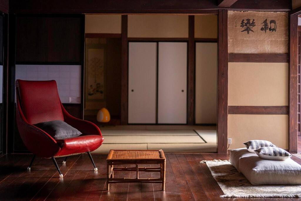 a living room with a red chair and a table at Hanakaijichi, Explore the crustal movement every thousand years in Kuroshima