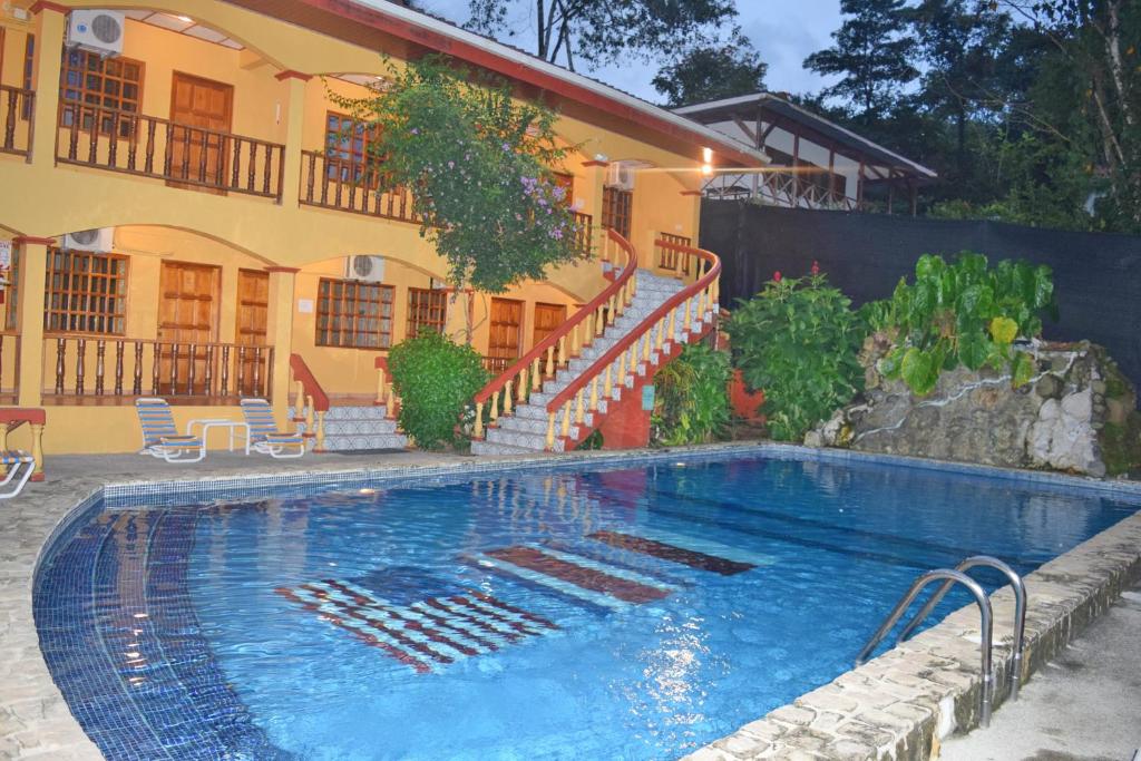 a large swimming pool in front of a house at Hotel Tres Banderas in Manuel Antonio