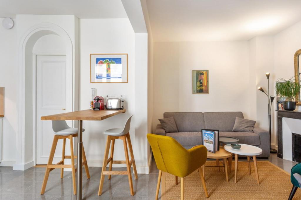 un salon avec un canapé, une table et des chaises dans l'établissement Appartement du Marché St Honoré - Welkeys, à Paris