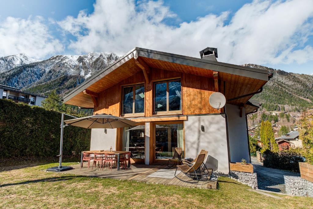 une maison avec une terrasse dotée d'une table et d'un parasol dans l'établissement Chalet Arve - Alpes Travel - Chamonix - Sleeps 10, à Chamonix-Mont-Blanc