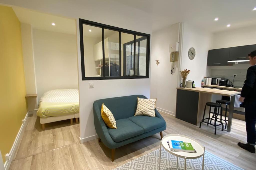 un salon avec une chaise bleue et une cuisine dans l'établissement Appart Hôtel Lille Beaux Arts - Mireille, à Lille