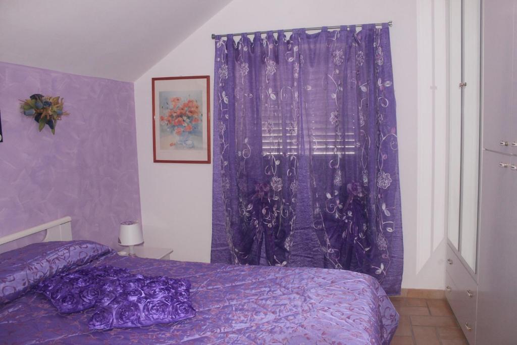 sypialnia z fioletowymi zasłonami i fioletowym łóżkiem w obiekcie B&B Angels w mieście Canosa Sannita