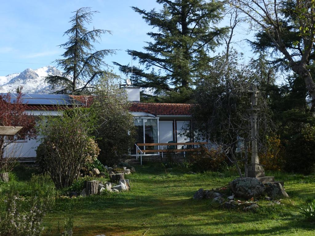 a house in a garden with mountains in the background at A Leira - Chalet con Piscina en Becerril de la Sierra in Becerril de la Sierra