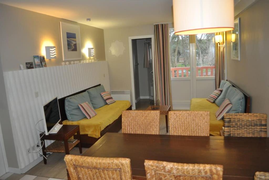 un salon avec une table et des chaises jaunes dans l'établissement Les jardins de la cote d opale 2 chambres, à Le Touquet-Paris-Plage