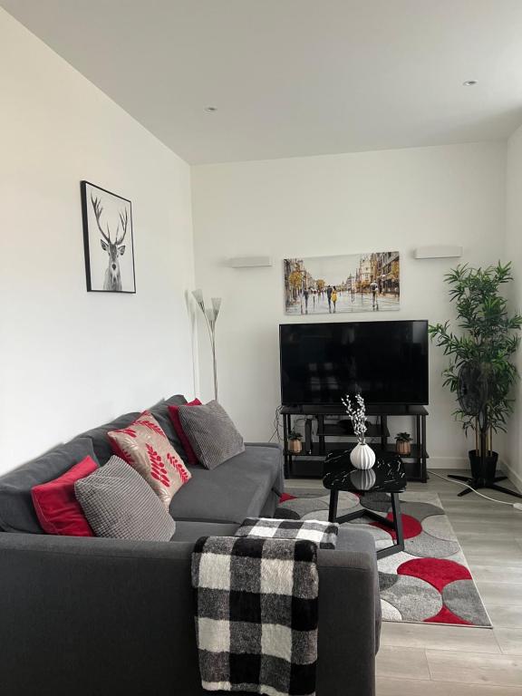 a living room with a couch and a flat screen tv at Stylish 2 bedrooms, 2 bathrooms with workspace in Milton Keynes in Milton Keynes