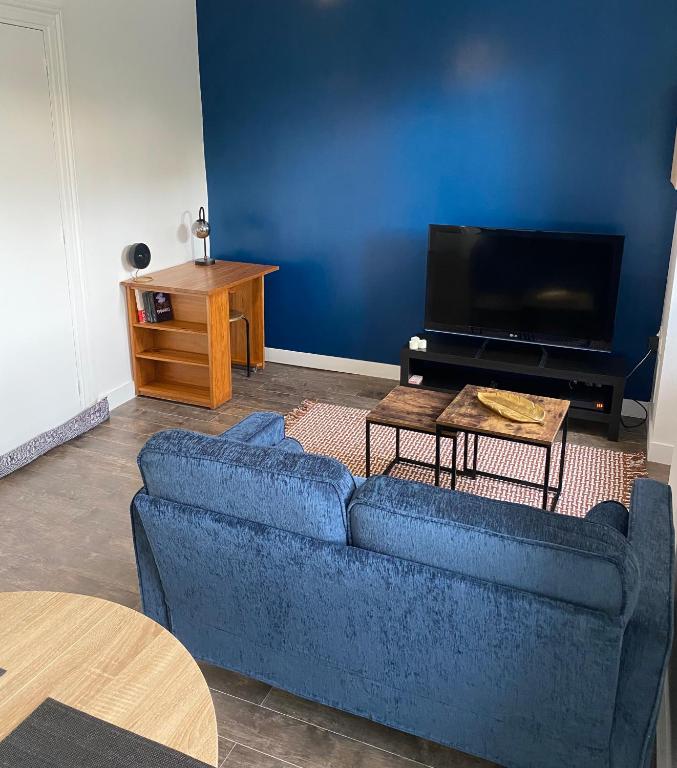 un salon avec un canapé bleu et une télévision dans l'établissement Appartement moderne proche commerces, à Brest